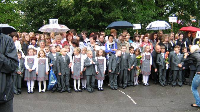 Мама Никиты накрывает его и товарищей зонтиком от дождя.