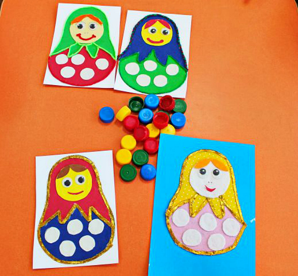 Вырезаем из фоамирана белого цвета кружочки и приклеиваем на платье матрешки.